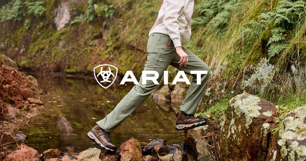 Women hiker wearing Ariat Traverse hiking boots and pants crossing a creek