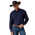 Man wearing a navy blue shirt, jeans, and a brown cowboy hat on a beige background