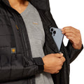 Person wearing a black jacket with Ariat branding, holding a phone.