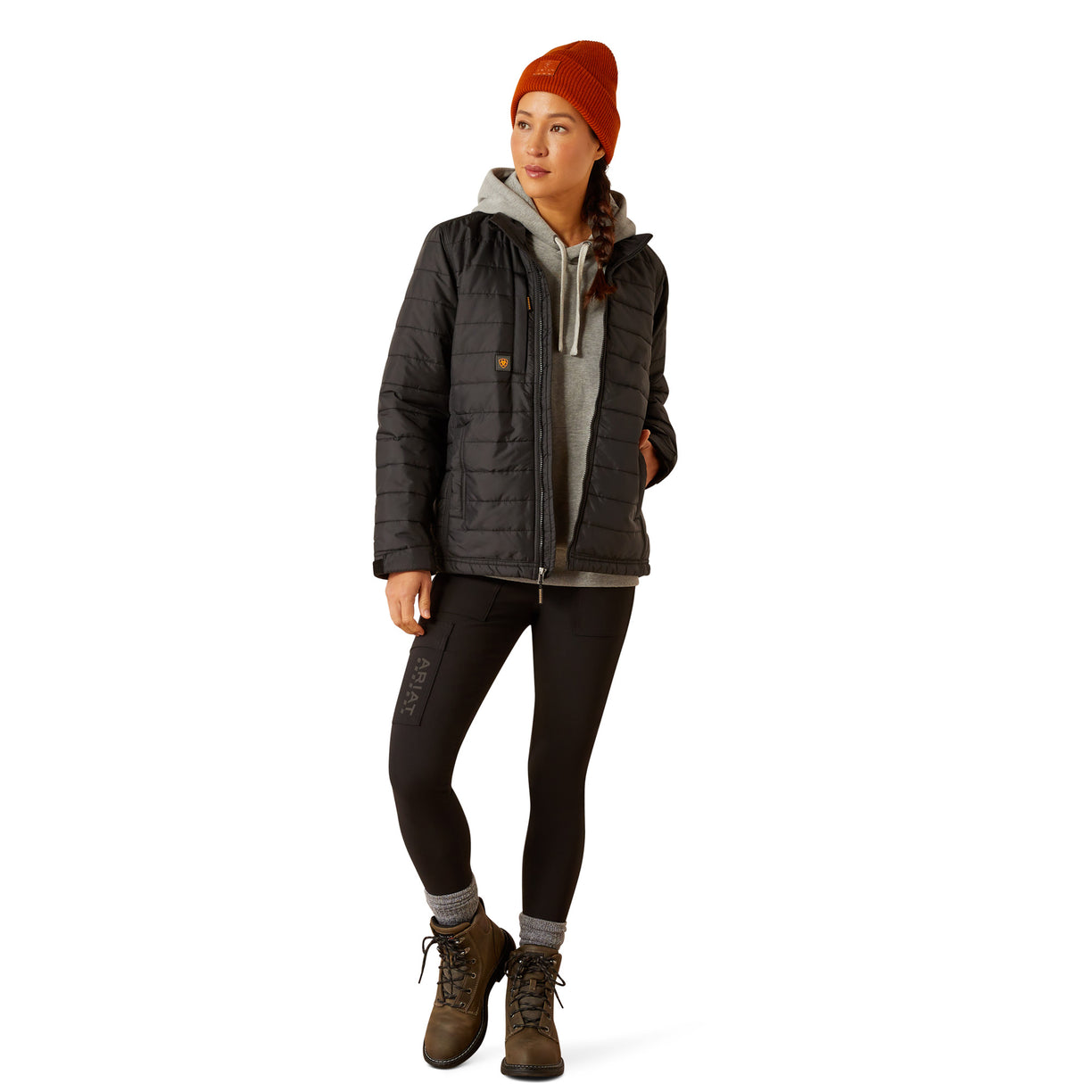 Person wearing a dark jacket, leggings, and boots on a white background