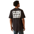 Person wearing a black t-shirt with 'Ariat Work' text on the back, standing against a white background
