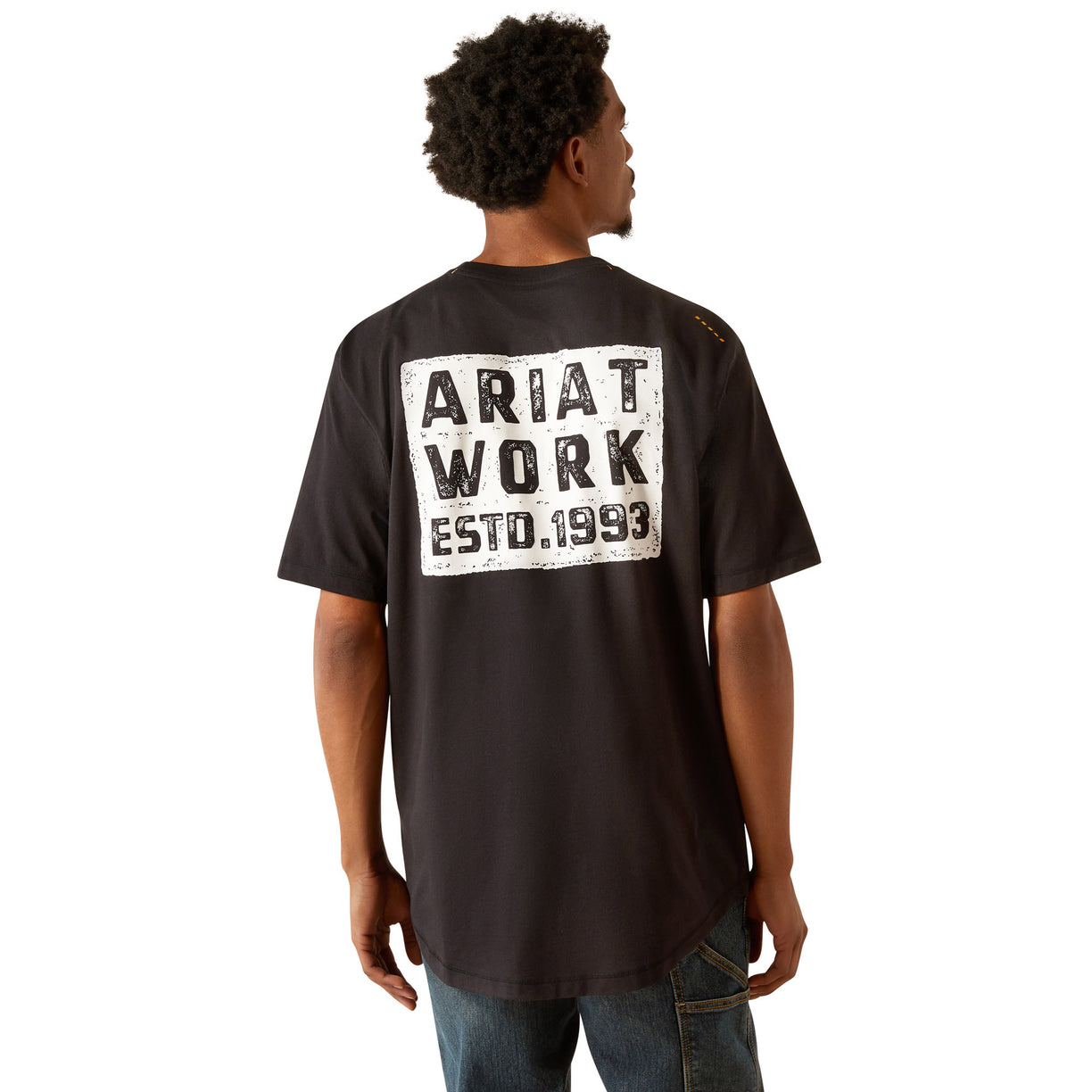 Person wearing a black t-shirt with 'Ariat Work' text on the back, standing against a white background
