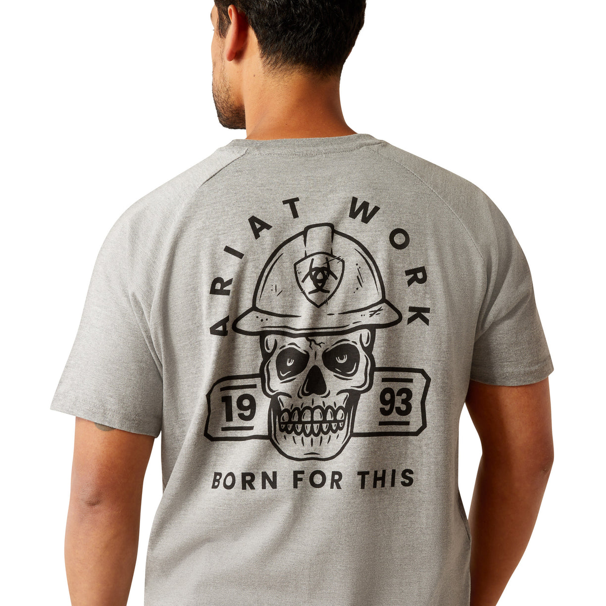 Man wearing a gray t-shirt with a skull and hard hat graphic on the back, on a white background