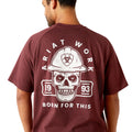 Man wearing a maroon t-shirt with a skull and hard hat graphic on the back, on a white background.