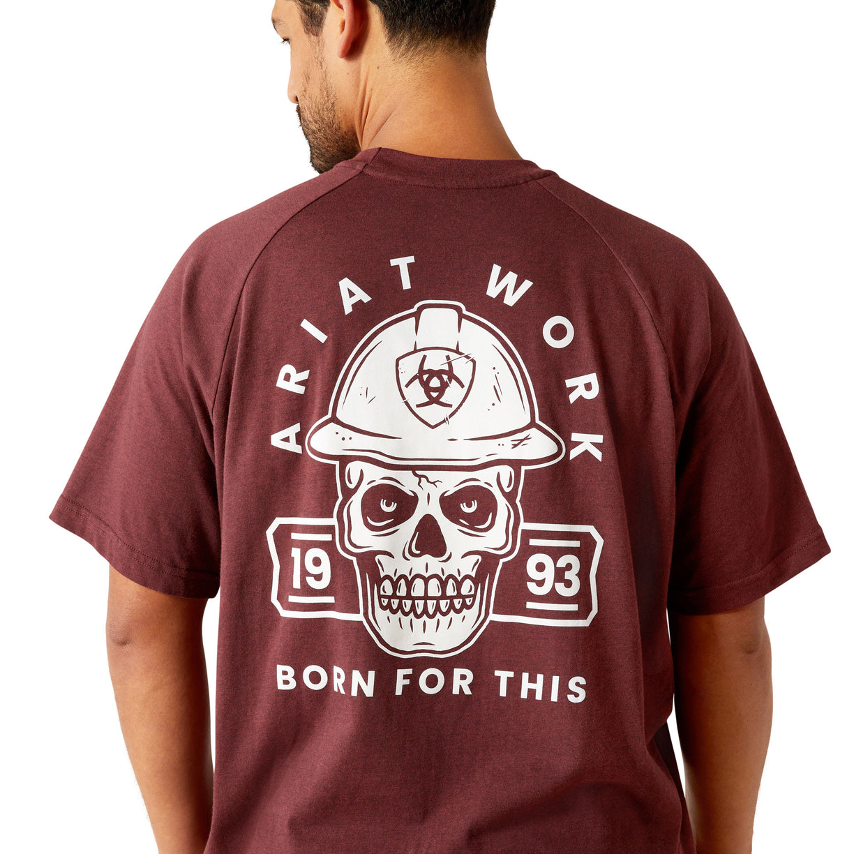 Man wearing a maroon t-shirt with a skull and hard hat graphic on the back, on a white background.