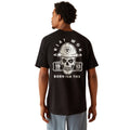 Person wearing a black t-shirt with a skull and hard hat graphic on the back.