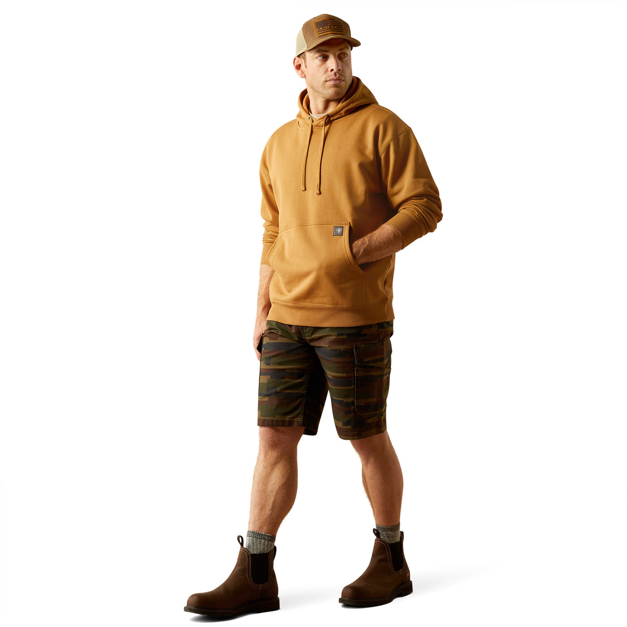 Man wearing a brown hoodie with Ariat Work branding and cap on a white background