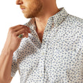 Man wearing a patterned shirt and jeans on a white background