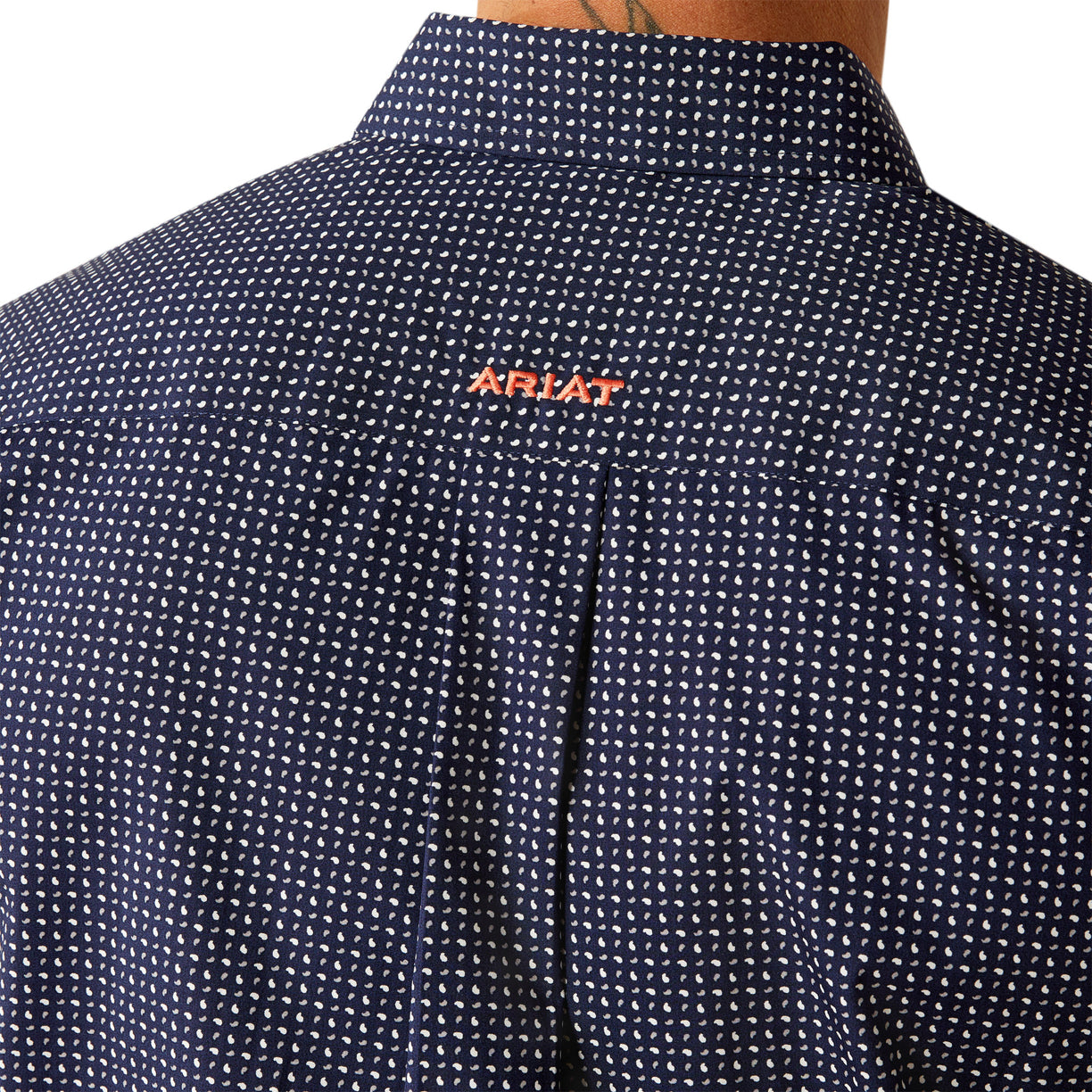 Man wearing a patterned dark shirt and dark pants on a white background