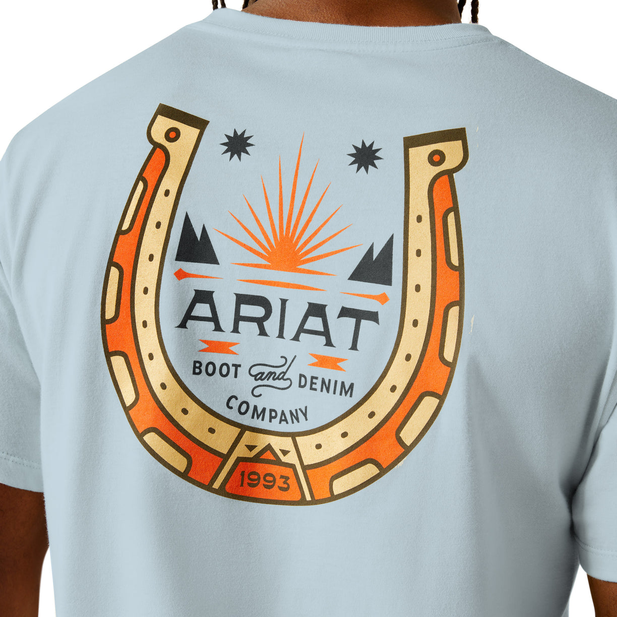 Light blue t-shirt with Ariat logo featuring a horseshoe and sun design on the back.