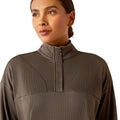 Woman wearing a brown long-sleeve athletic top and leggings on a white background