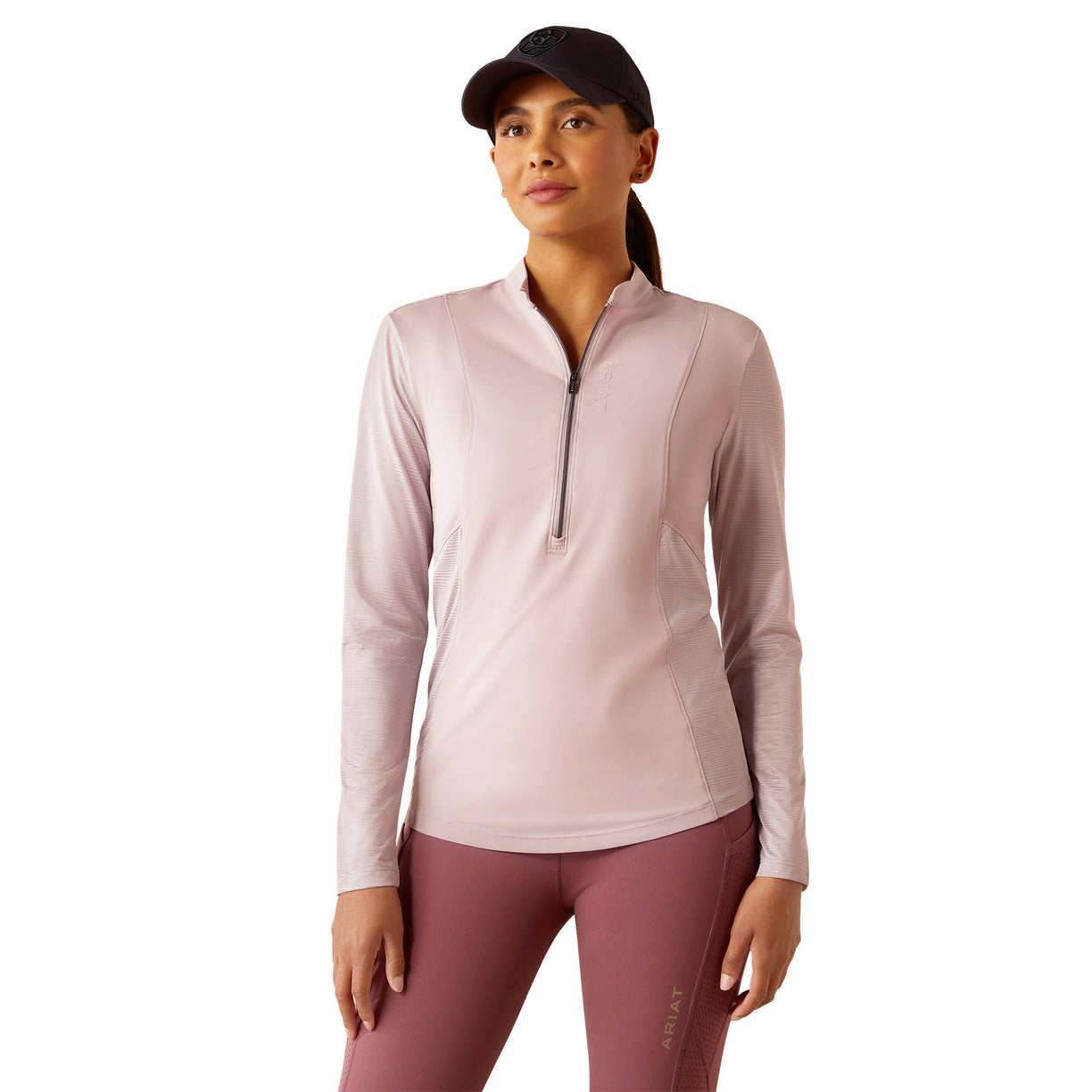 Woman wearing a light pink long-sleeve athletic top and maroon leggings on a white background