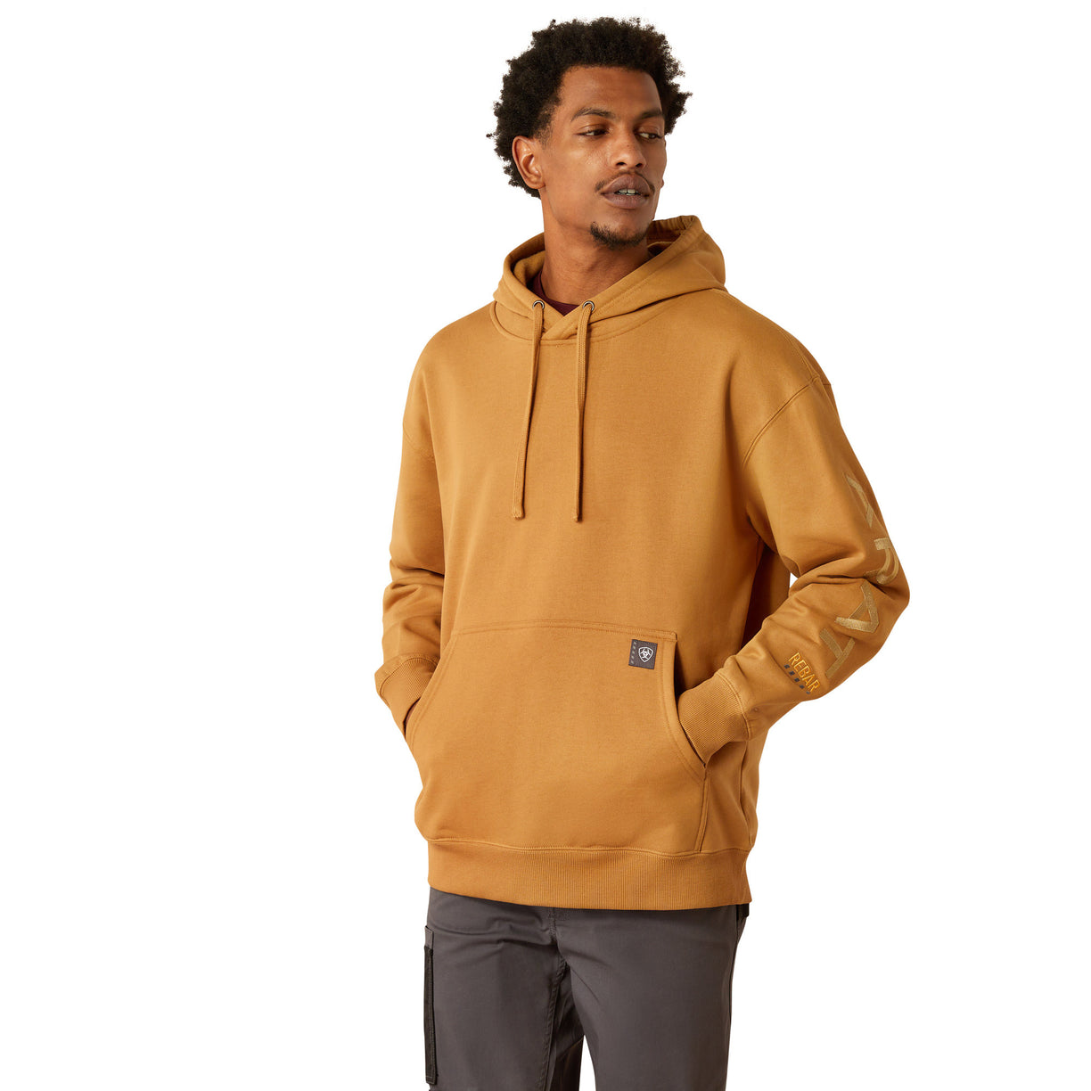 Man wearing a mustard yellow hoodie with Ariat branding on a white background