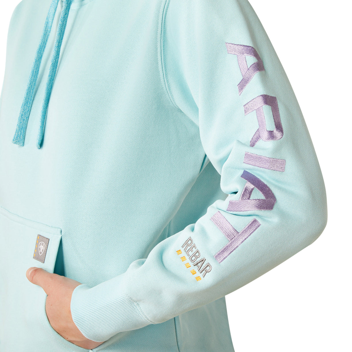 Person wearing a light blue hoodie with 'Ariat' branding on a white background