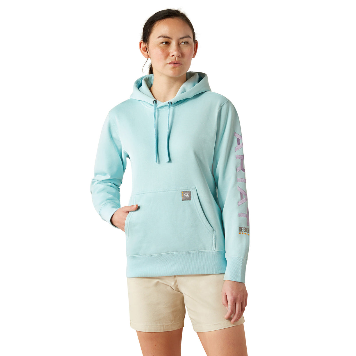 Person wearing a light blue hoodie with 'Ariat' branding on a white background