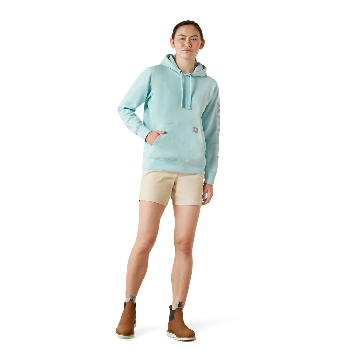 Person wearing a light blue hoodie with 'Ariat' branding on a white background