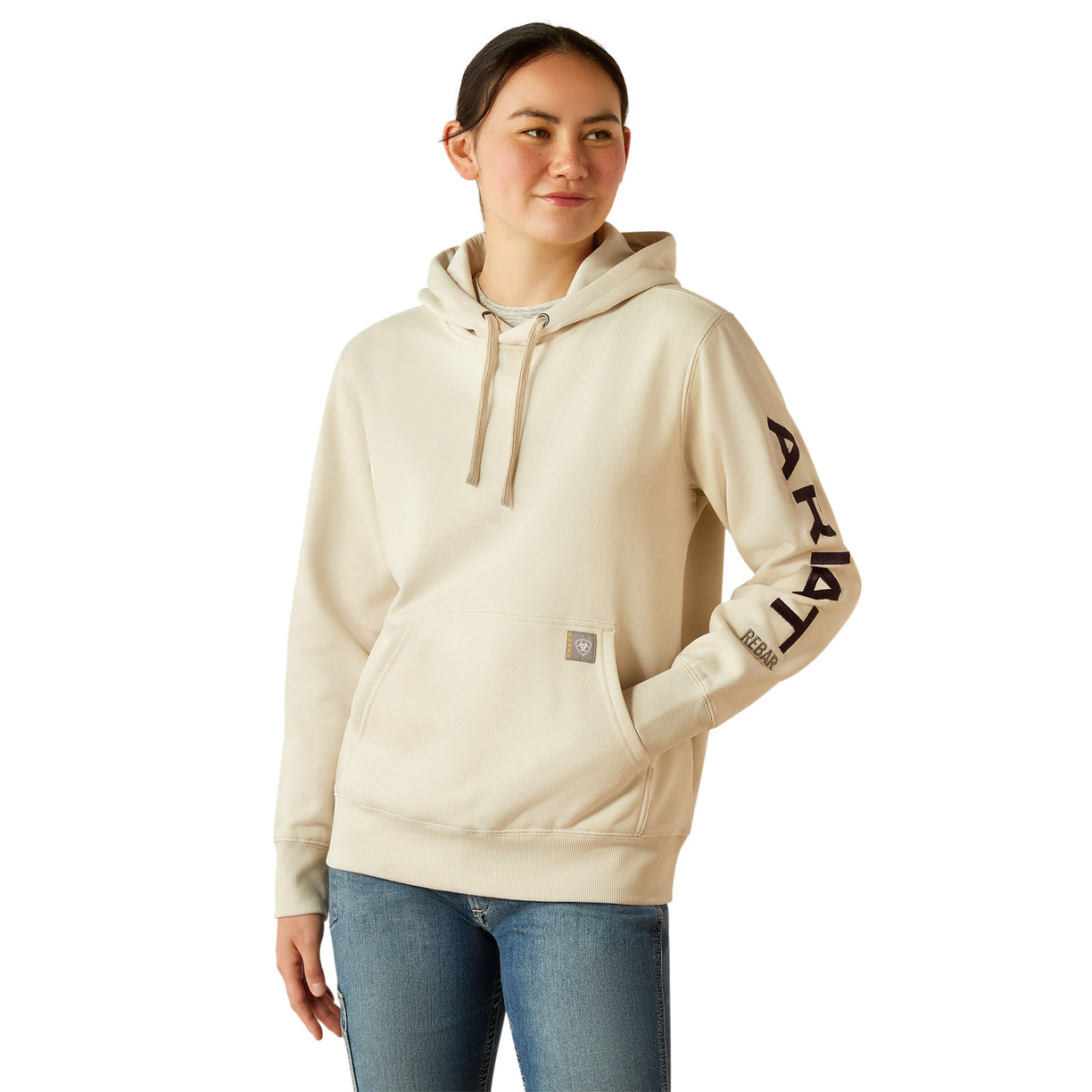 Woman wearing a beige hoodie with Ariat brand logo on a white background