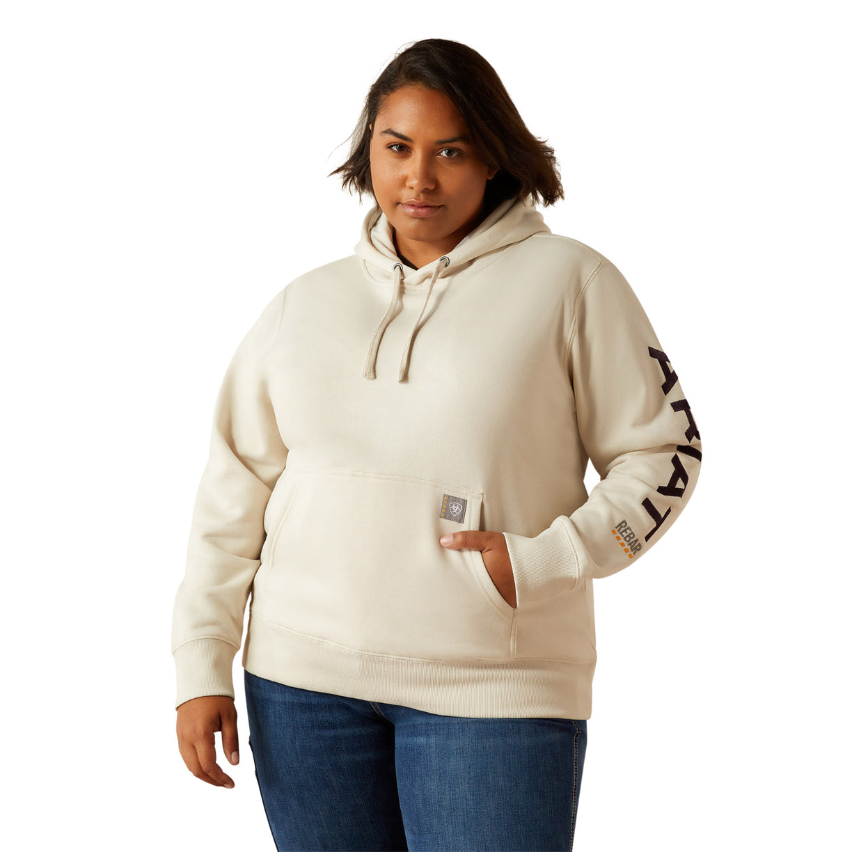 Woman wearing a beige hoodie with Ariat brand logo on a white background