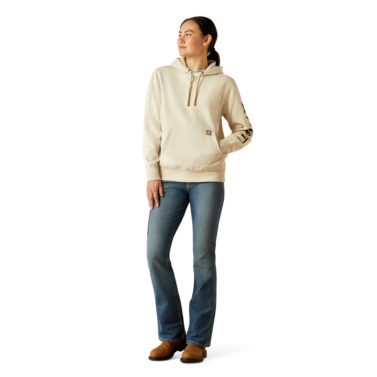 Woman wearing a beige hoodie with Ariat brand logo on a white background