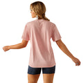 Woman wearing a pink t-shirt with white text, denim shorts, and a cowboy hat on a white background