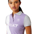 Woman wearing a purple and white striped polo shirt with 'Ariat' branding on a white background