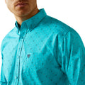 Man wearing a turquoise patterned shirt with a brand logo on a white background
