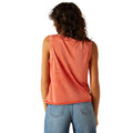 Person wearing a sleeveless orange top and blue jeans on a white background