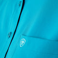 Close-up of a blue shirt with a logo on the chest pocket.