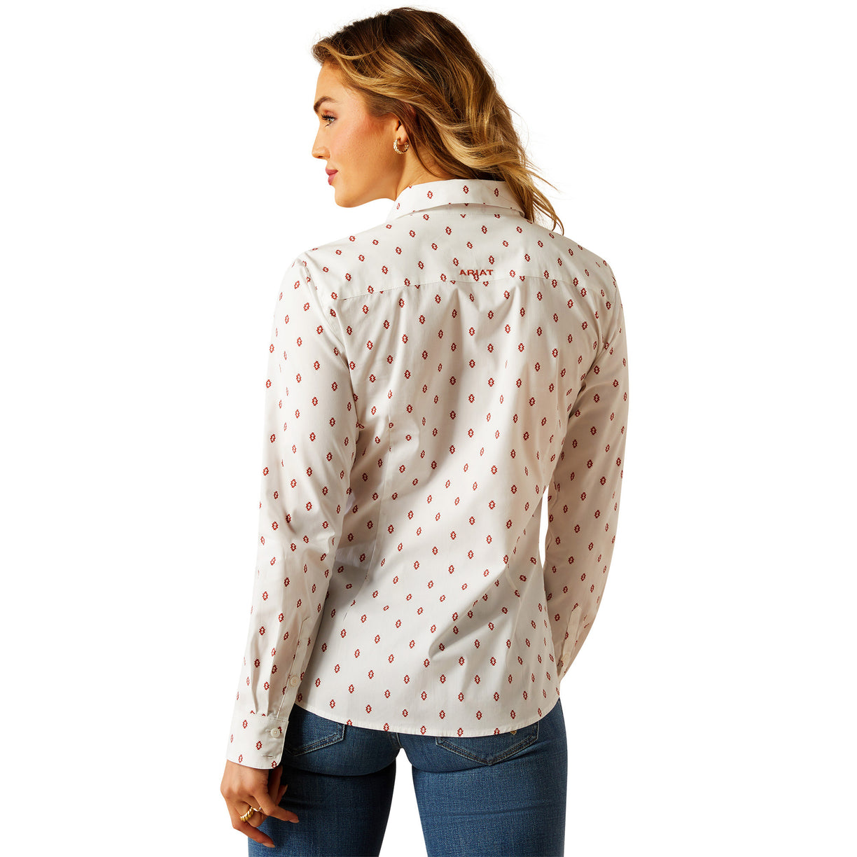 Woman wearing a white blouse with red pattern and blue jeans on a white background