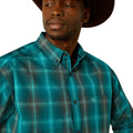 Man wearing a teal plaid shirt with a brand logo on a white background