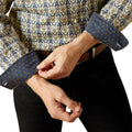 Person adjusting the cuff of a patterned shirt with a white background