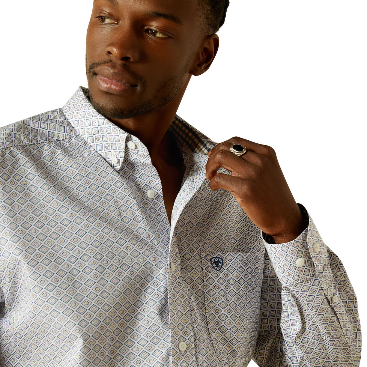 Man wearing a patterned shirt with a visible brand logo on a white background
