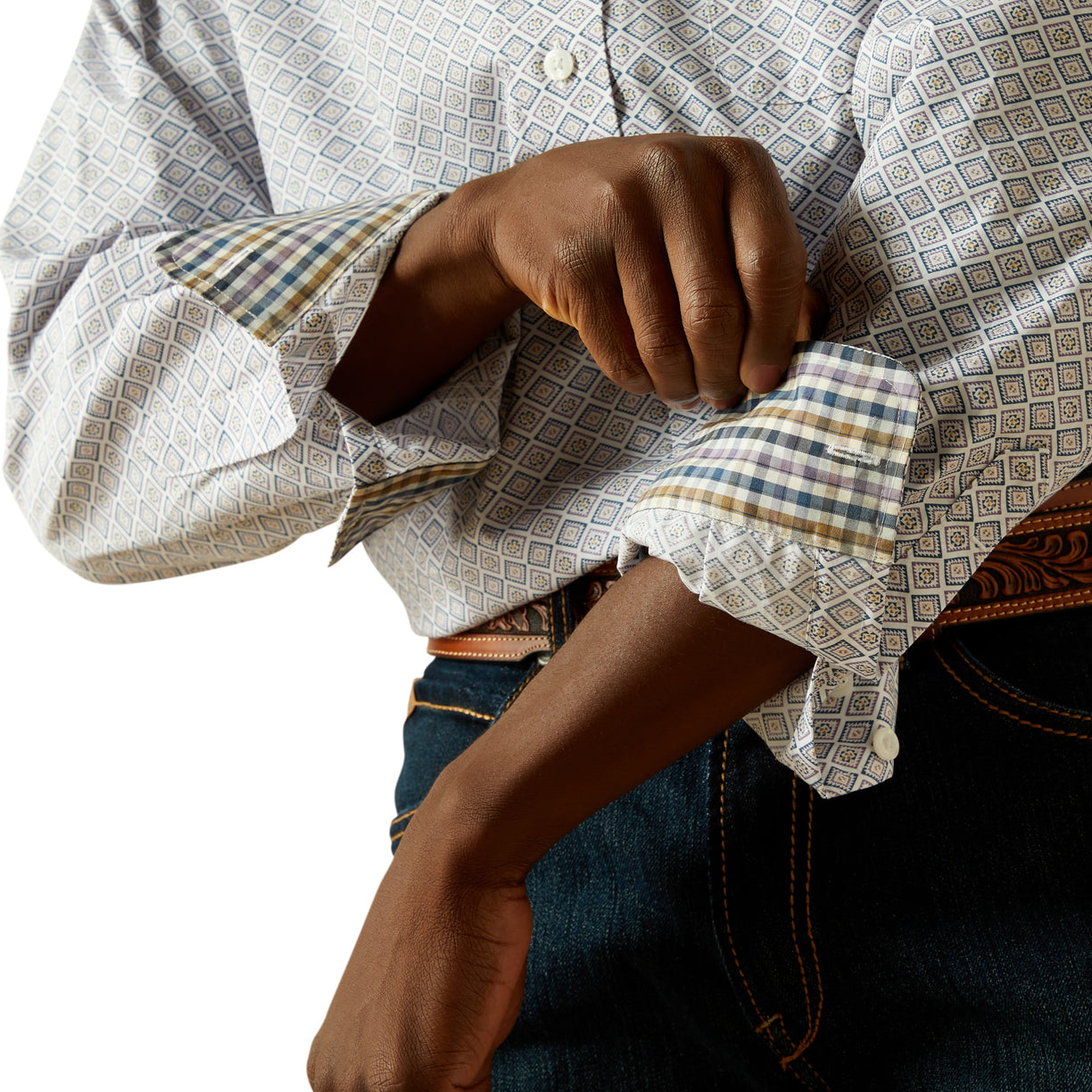 Person wearing a patterned shirt with rolled-up sleeves and jeans.