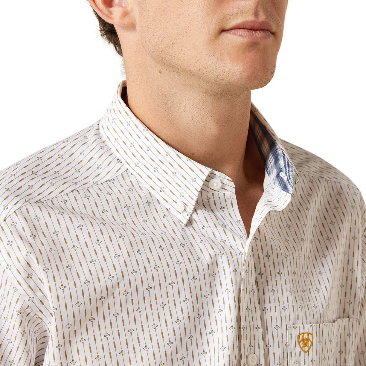 Close-up of a man wearing a patterned shirt with a visible brand logo.