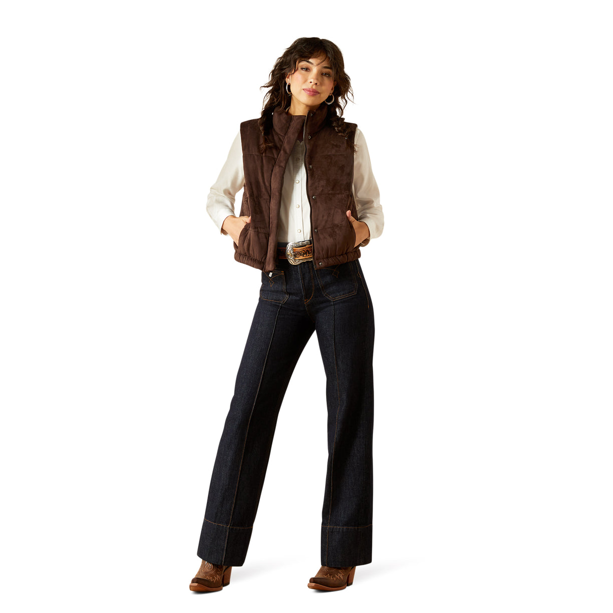 Woman wearing a brown vest, white shirt, and dark jeans on a white background