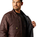 Man wearing a brown quilted jacket with a brand logo on a white background