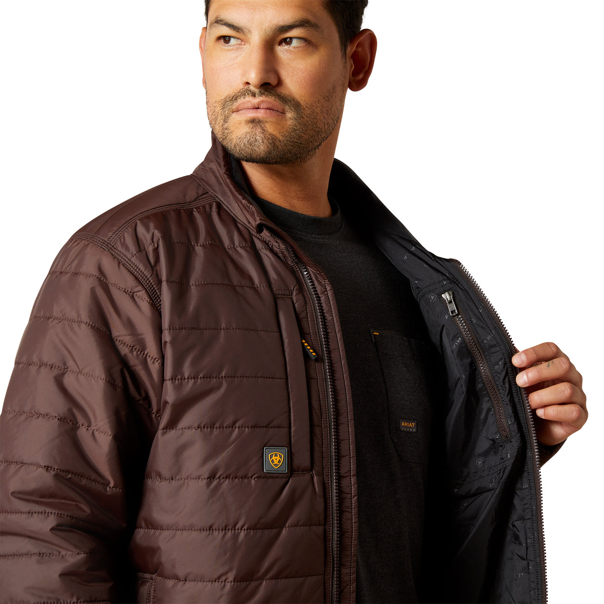 Man wearing a brown quilted jacket with a brand logo on a white background