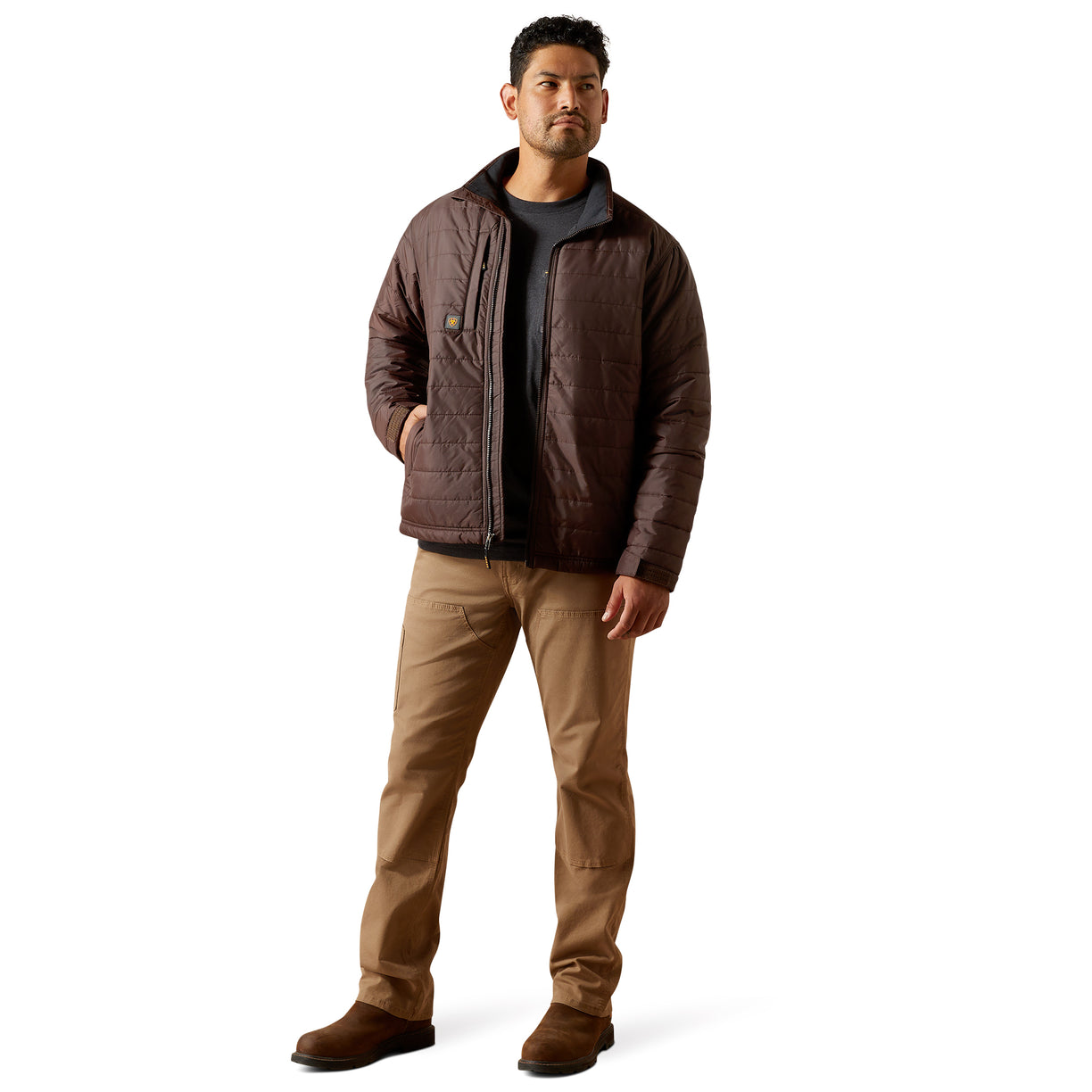 Man wearing a brown quilted jacket and tan pants on a white background