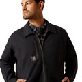 Man wearing a black jacket with a plaid shirt underneath on a white background
