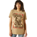 Woman wearing a tan t-shirt with a graphic design and 'Ariat' branding.