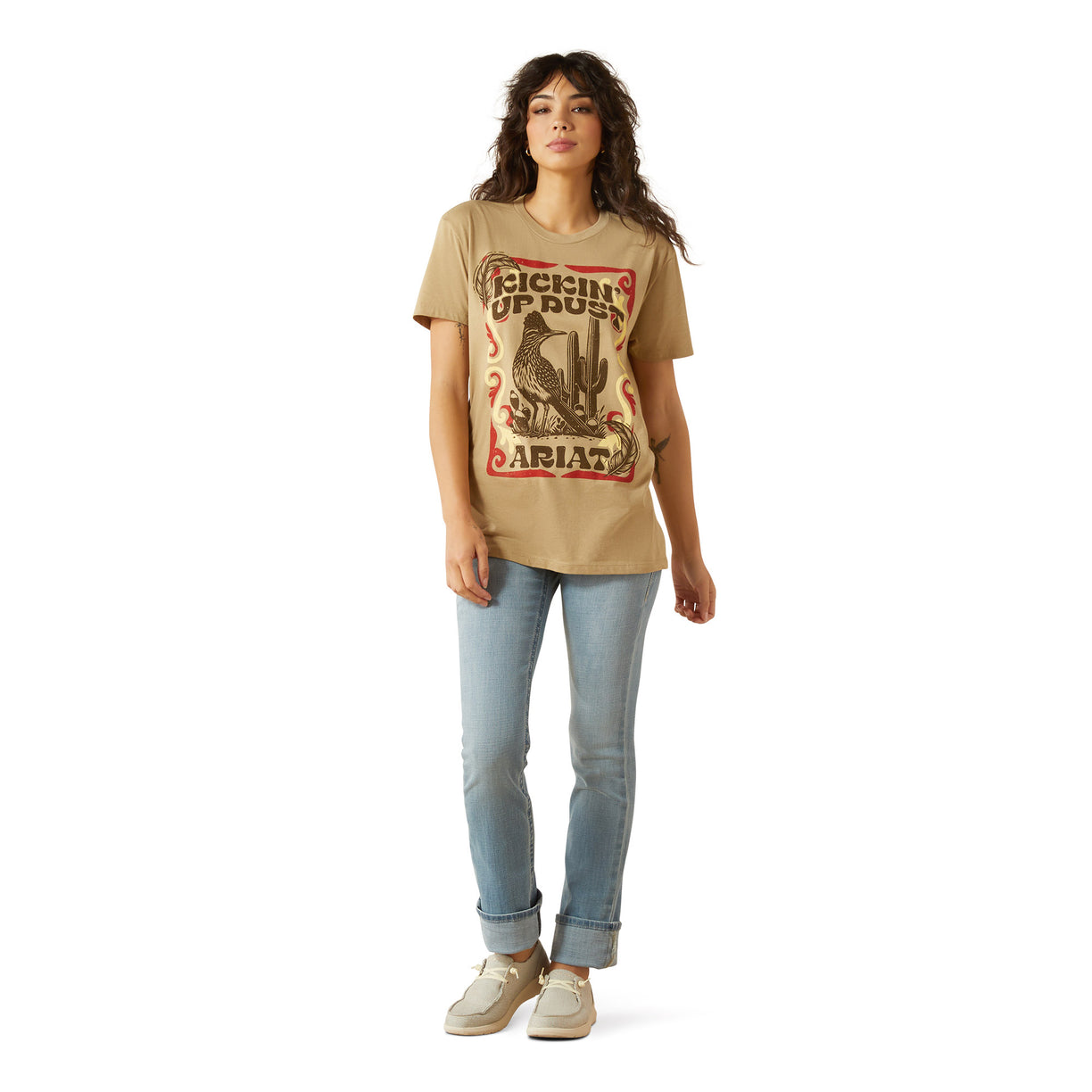 Woman wearing a beige t-shirt with graphic design and text, standing against a white background