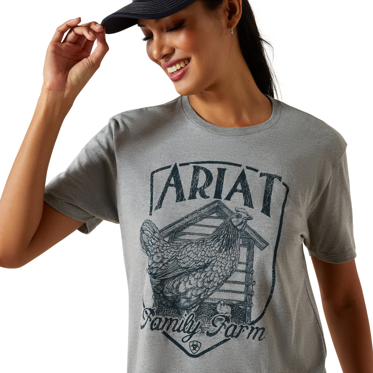 Woman wearing a gray t-shirt with 'Ariat Family Farm' graphic design.