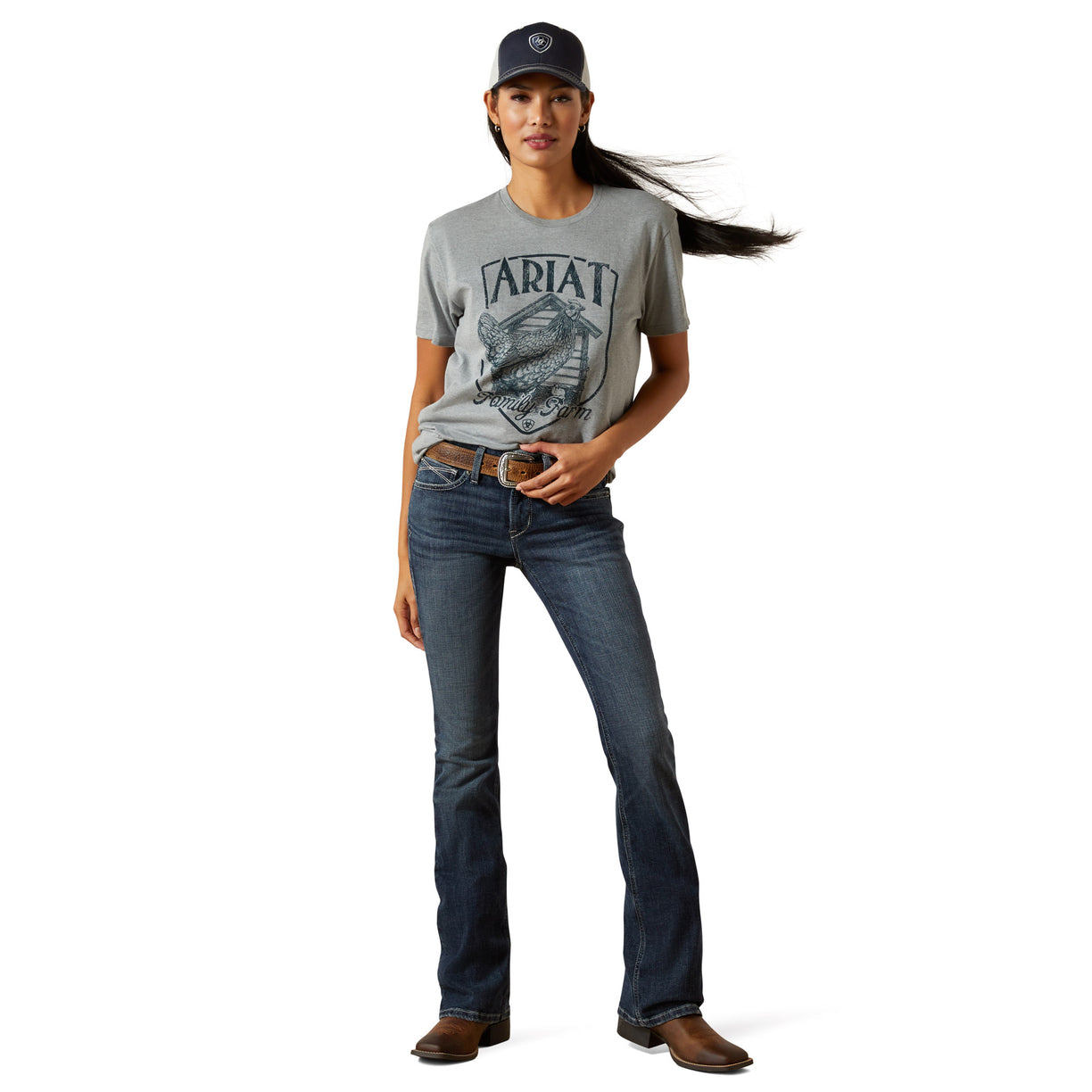 Woman wearing a gray Ariat t-shirt and blue jeans on a white background
