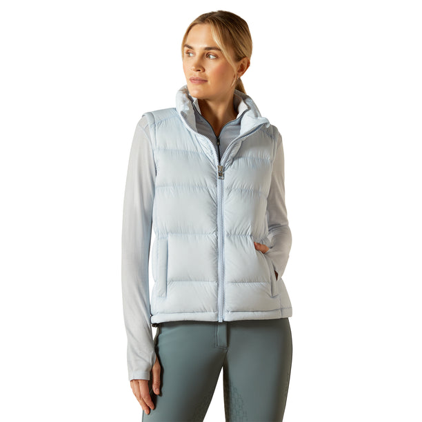 Woman wearing a light blue puffer vest over a white shirt on a white background