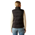 Person wearing a black puffer vest with 'Ariat' branding on a white background