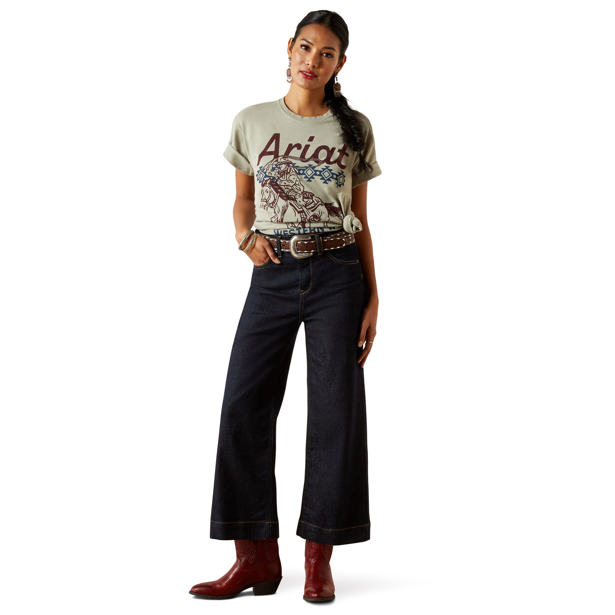 Woman wearing a graphic t-shirt, dark jeans, and red boots on a white background