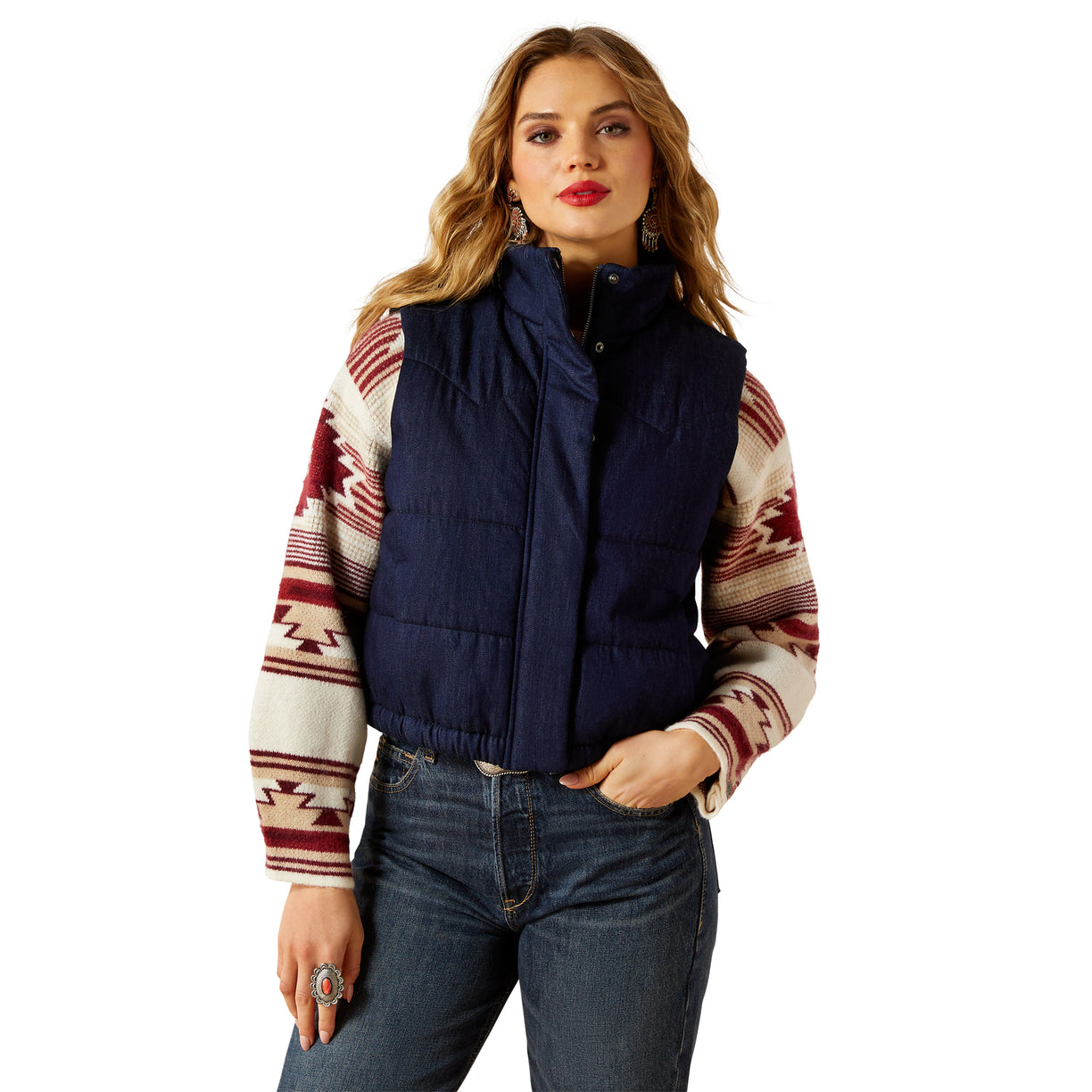 Woman wearing a navy puffer vest over a patterned sweater on a white background