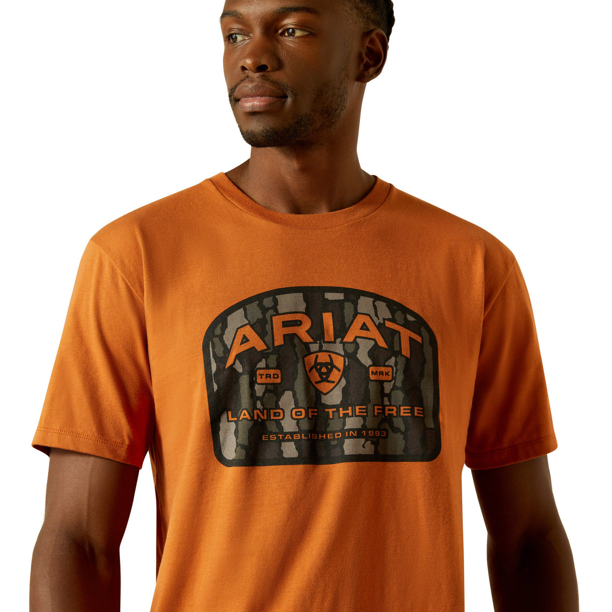 Man wearing an orange Ariat t-shirt with a logo on a white background