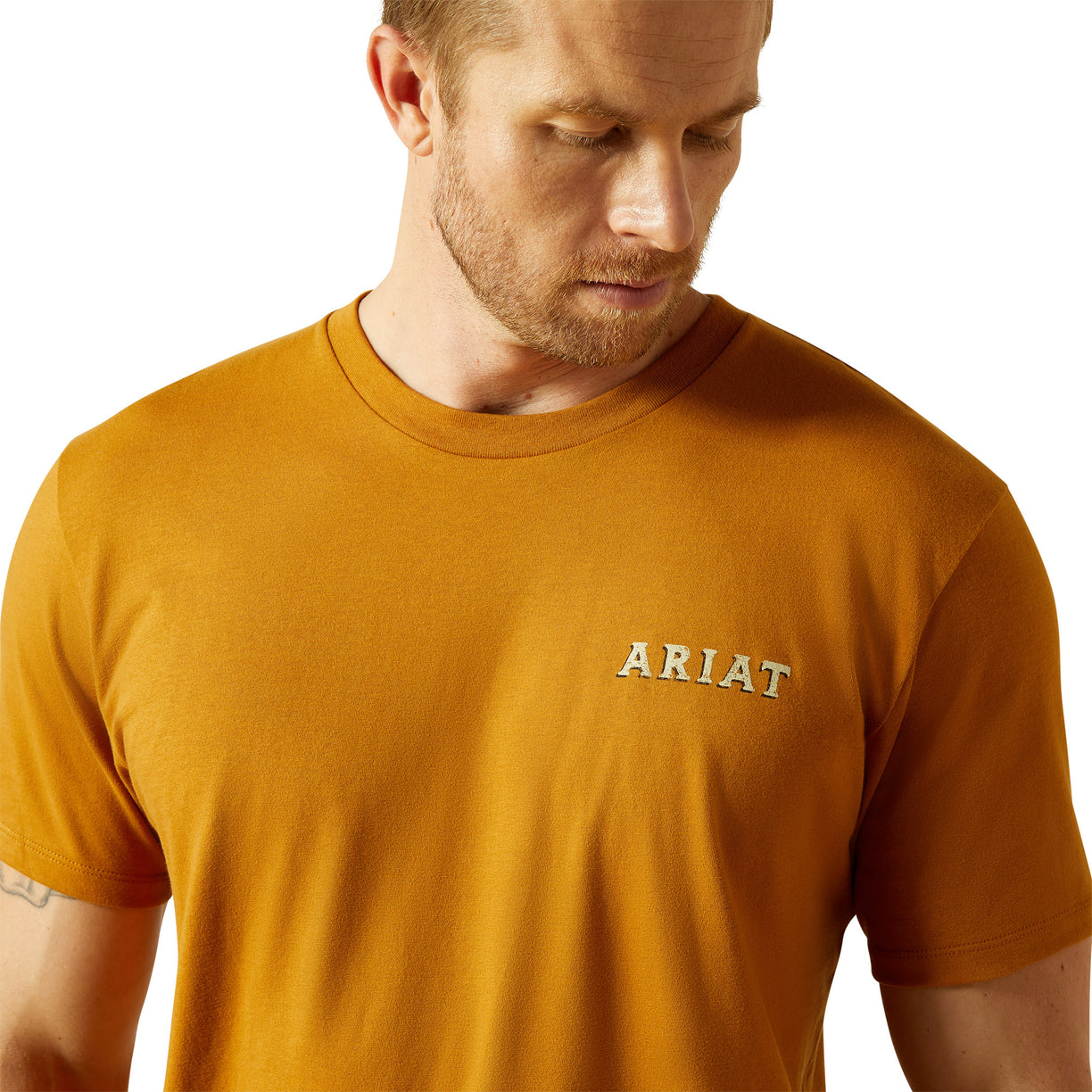 Man wearing a mustard yellow Ariat t-shirt on a white background