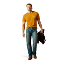 Man wearing a mustard yellow t-shirt and blue jeans holding a black bag on a white background